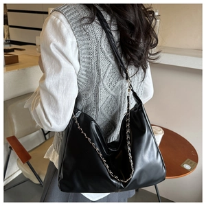 Detailed side view of a large black vintage faux leather tote bag with chain strap