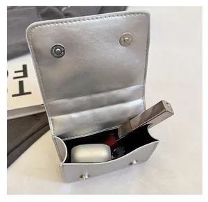 Detail view of silver mini crossbody bag showing internal space for lipstick and earphones