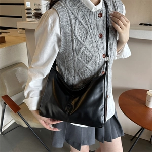 Retro black PU leather tote bag with shoulder strap worn by a model in a cafe setting