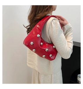 Gros plan d'un sac porté épaule en cuir ciré rouge avec rivets métalliques argentés