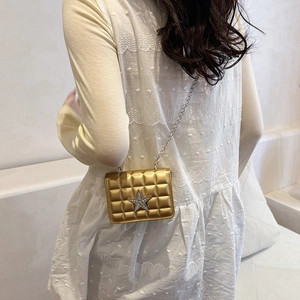 Chic gold mini crossbody bag with star accent and silver chain strap on model