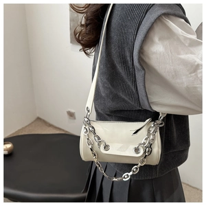 Detail view of cream cylinder bag with silver chunky chain and adjustable shoulder strap
