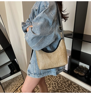 Detail of hand-woven hobo bag with black leather trim and gold hardware on model shoulder