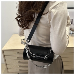 Detail view of black cylinder bag with silver chain strap and white text branding