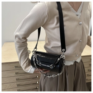 Detail of black cylindrical crossbody bag with chunky silver chain and wide strap