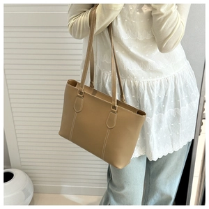 Close-up of large brown faux leather tote bag with stylish white contrast stitching