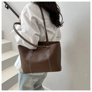 Detail of coffee brown tote bag featuring white contrast stitching and long shoulder straps
