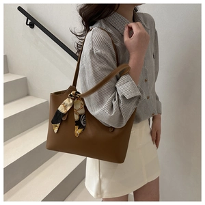 Caramel brown tote bag detail featuring a decorative silk scarf on the handle