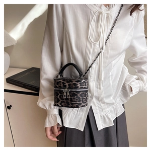 Detail of leopard print bucket bag featuring chain strap and double zipper closure