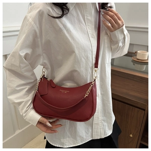 Detail of red crescent leather bag with gold chain and litchi grain texture on model