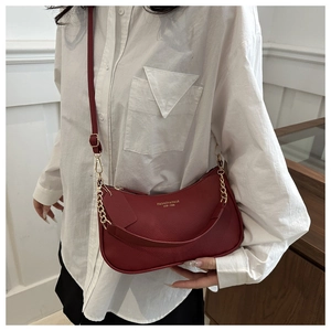 Deep red textured leather underarm bag with gold chain strap on female model