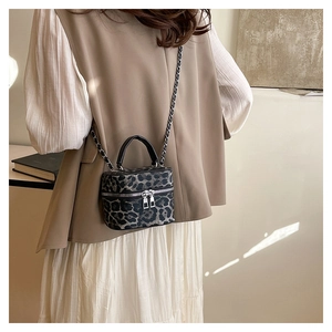 Detail of leopard print bucket bag with metal chain strap and dual zippers