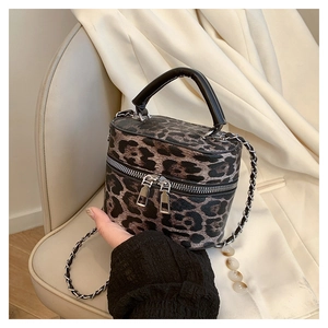 Detail of leopard print bucket bag featuring double zippers and silver chain strap