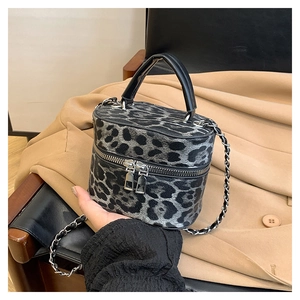Detail of leopard print bucket bag featuring leather handle and silver dual zippers