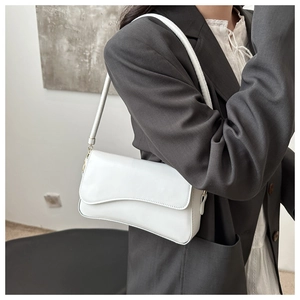 Close-up of a white leather underarm bag featuring a flap closure and slim shoulder strap