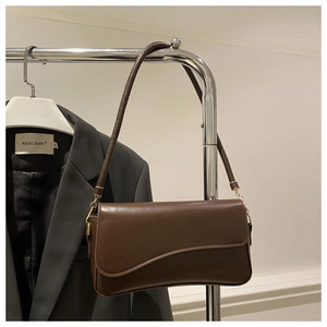 Detail of dark brown leather underarm bag with asymmetric wave-cut flap and gold hardware