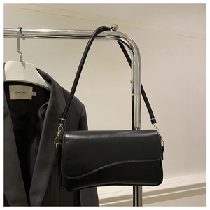 Detail of black leather underarm bag with unique wavy flap design and gold hardware
