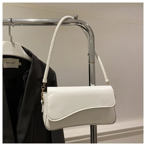 Detail of white leather underarm bag featuring irregular wave flap and gold hardware