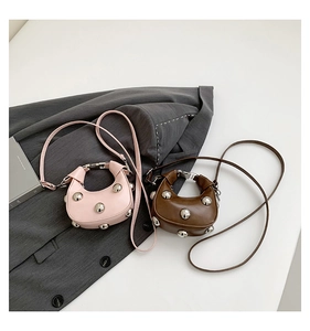 Detail of trendy half-moon bags with large silver studs in pink and brown faux leather