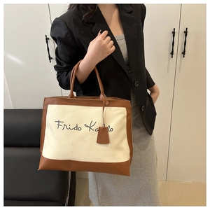 Close-up of canvas tote bag with Frida Kahlo script and premium brown leather trim