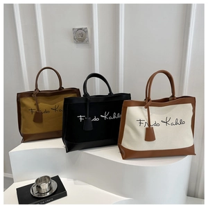 Close-up of contrast leather canvas tote bags with Frida Kahlo lettering and pendant