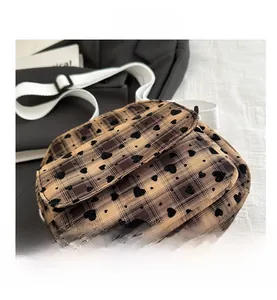 Detail view of the brown plaid canvas bag with black heart flocking and adjustable strap