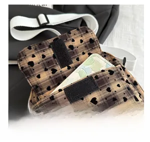 Close-up of brown plaid heart-patterned crossbody bag showing velcro and interior pocket