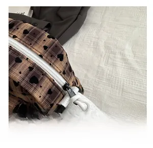Detail showing the smooth white zipper and metal puller of the plaid canvas bag