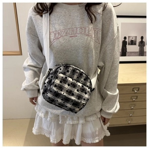 Detail of checkered canvas crossbody bag with black heart print and front zipper pocket