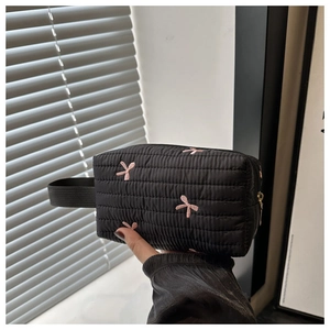 Close-up of quilted black nylon pouch featuring delicate pink embroidered small bows