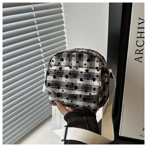 Detail of checkered canvas crossbody bag with black heart patterns and adjustable strap