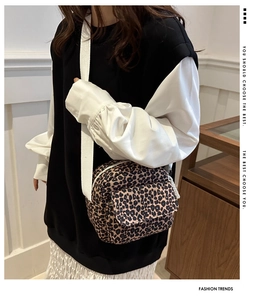 Detail of leopard print crossbody bag featuring a front pocket and wide canvas strap