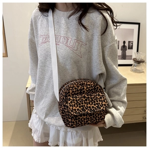 Detailed view of leopard print crossbody bag with front flap pocket and wide strap