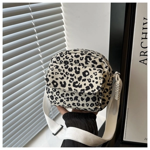 Detail of leopard print canvas crossbody bag with white adjustable strap and front pocket