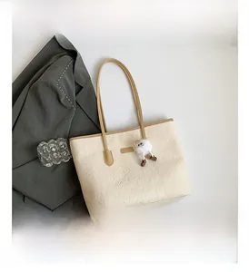 Détail du sac cabas crème avec motifs de chats embossés et breloque en peluche