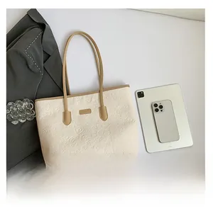 Détail du sac cabas crème avec motifs d'ours embossés et anses en cuir marron