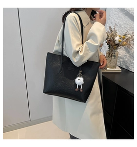 Détail du sac cabas noir gaufré avec un joli pendentif en peluche blanc de monstre