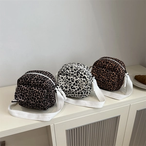 Three stylish leopard print crossbody bags in various colors with wide woven straps