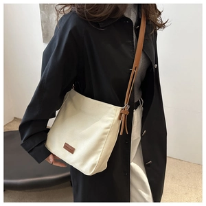 Détail du sac cabas minimaliste en toile beige avec bandoulière en cuir marron