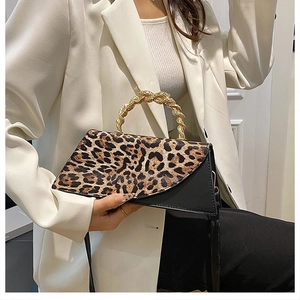 Detail of leopard print flap handbag featuring unique twisted gold metal handle and black base