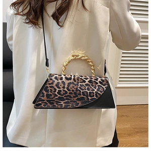 Detail of leopard print patchwork handbag with gold woven handle on white blazer
