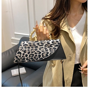 Detail view of leopard print panel and spiral gold metal handle on a black handbag