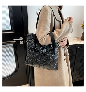 Close-up of quilted black puffer tote bag with diamond stitching and long strap