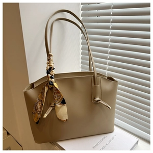 Detail of khaki tote bag featuring a decorative baroque silk scarf on the handle