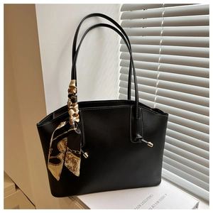 Detail of black matte leather tote bag with vintage scarf accent and metal bead trim