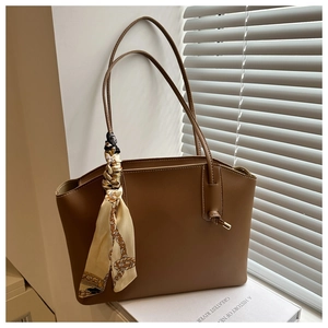 Brown leather tote bag detail with decorative floral silk scarf and fine white stitching