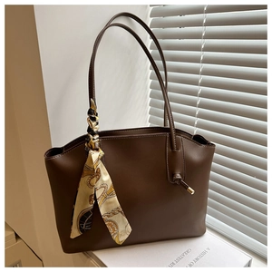 Detail of dark brown faux leather tote bag with printed silk scarf wrapped around handle