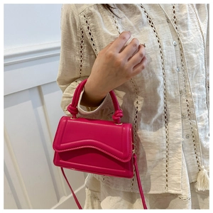 Detail van rozerode handtas met unieke gegolfde flap en cilindrisch bovenhandvat