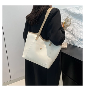 Sac fourre-tout crème minimaliste avec anses marron clair porté par un mannequin en studio