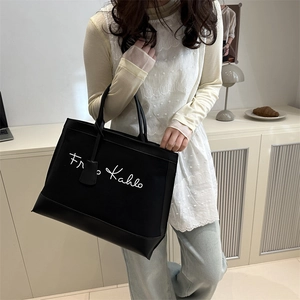 Large black canvas tote bag with Frida Kahlo lettering and leather handles